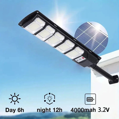 Black rectangular solar LED street light mounted on a white wall, featuring multiple light panels and a solar cell.
