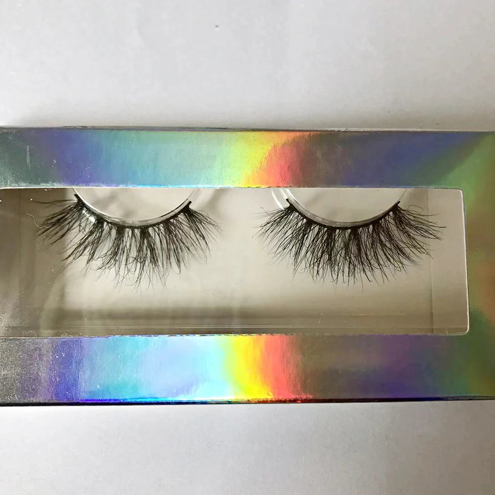 Pair of black 3D mink false eyelashes with a soft band, showcased in a vibrant holographic rectangular display box.