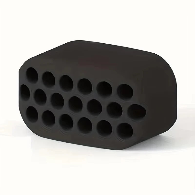 Black silicone jawline training block with a rectangular shape and a grid of circular holes on the front face.