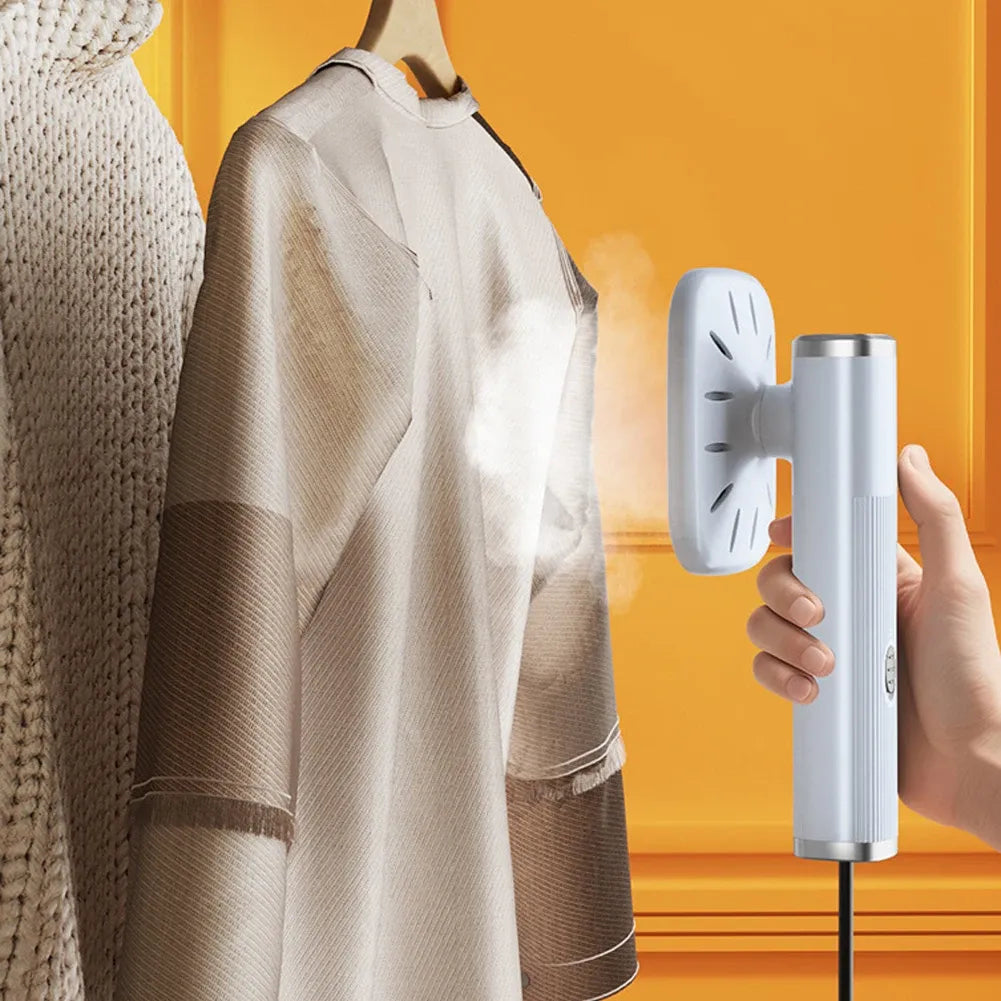 Handheld clothes steamer smoothing wrinkles on a hanging blouse with continuous steam against a warm background.