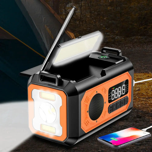 Black and orange emergency weather radio with antenna, reading lamp, solar panels, and digital display, charging a phone.