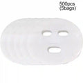 A stack of five thin, white, disposable facial mask sheets with cutouts for eyes, nose, and mouth.