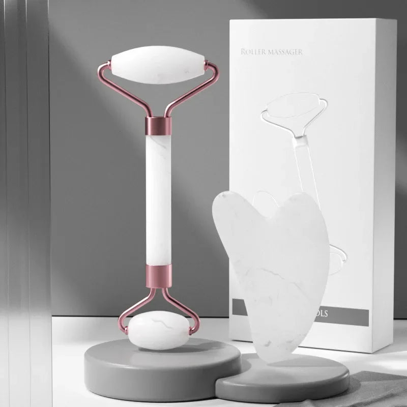 White facial massage roller with metallic rose gold accents and a matching heart-shaped white gua sha tool.