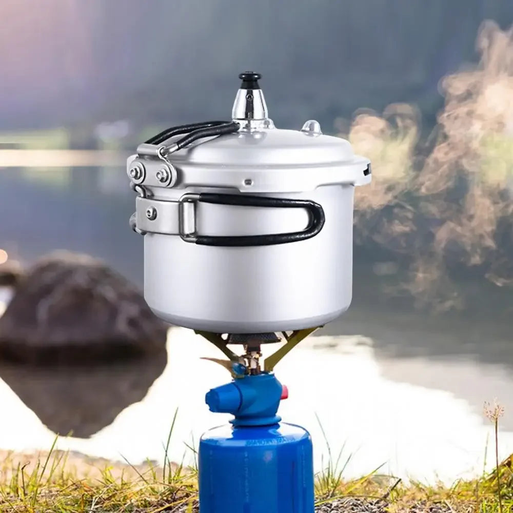 Silver pressure cooker with steam vent above a blue gas burner canister