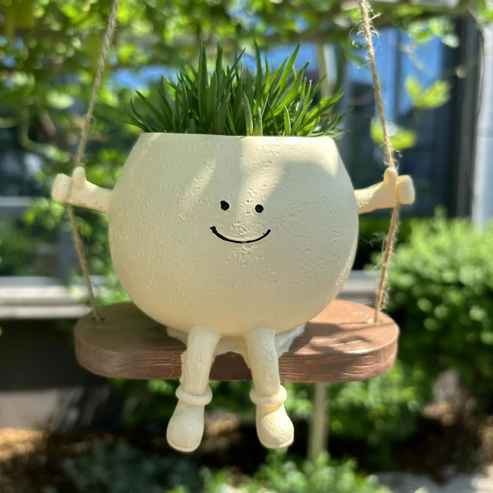 Outdoor rocking swing face planter pot with hanging ropes and green grass