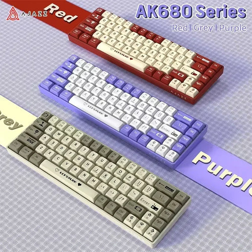 Three AJAZZ AK680 65% wired mechanical keyboards in red, purple, and grey with custom "LET'S PLAY!" spacebars.