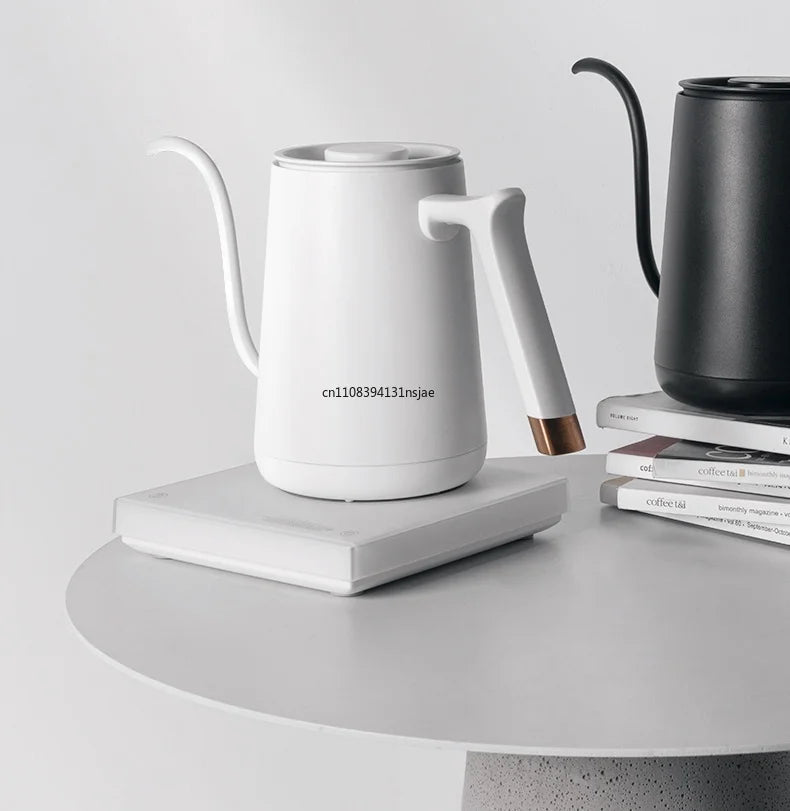 Modern matte white gooseneck electric pour-over coffee kettle with copper handle accent on a matching square base.