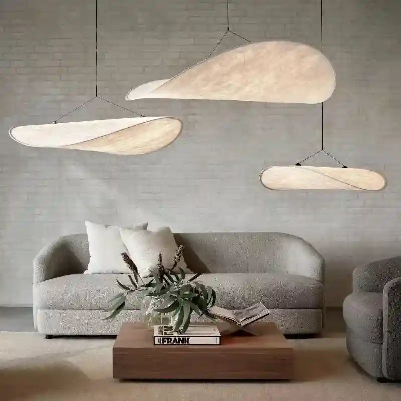 Three cloud-shaped pendant lights with textured, off-white fabric shades suspended over a living room sofa.