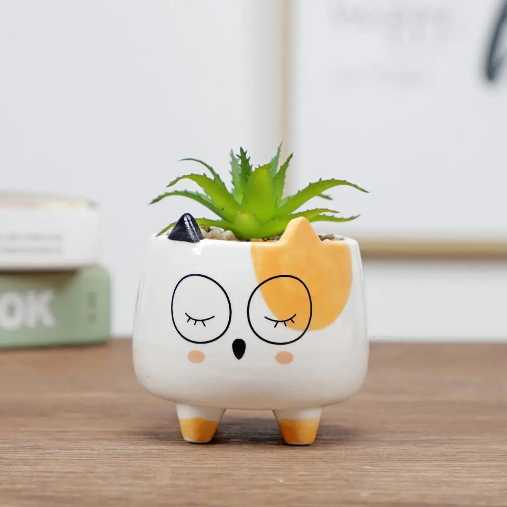 Adorable ceramic cat-face planter with green succulent, orange ears, and sleepy eyes