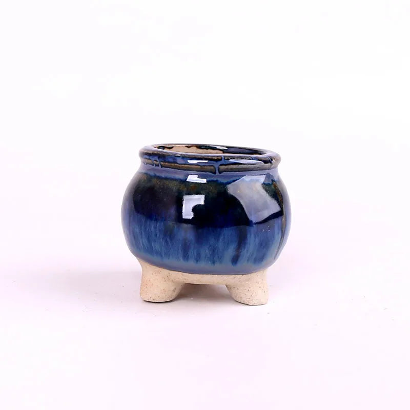 Mini ceramic flowerpot for succulent, dark blue glossy glaze with white crackle accents, three feet.