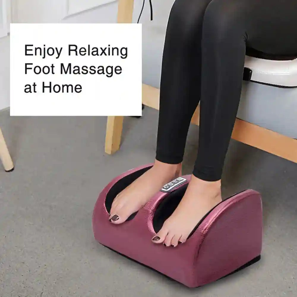 Woman using a metallic pink electric shiatsu foot massager with heat and kneading rollers for home pain relief.