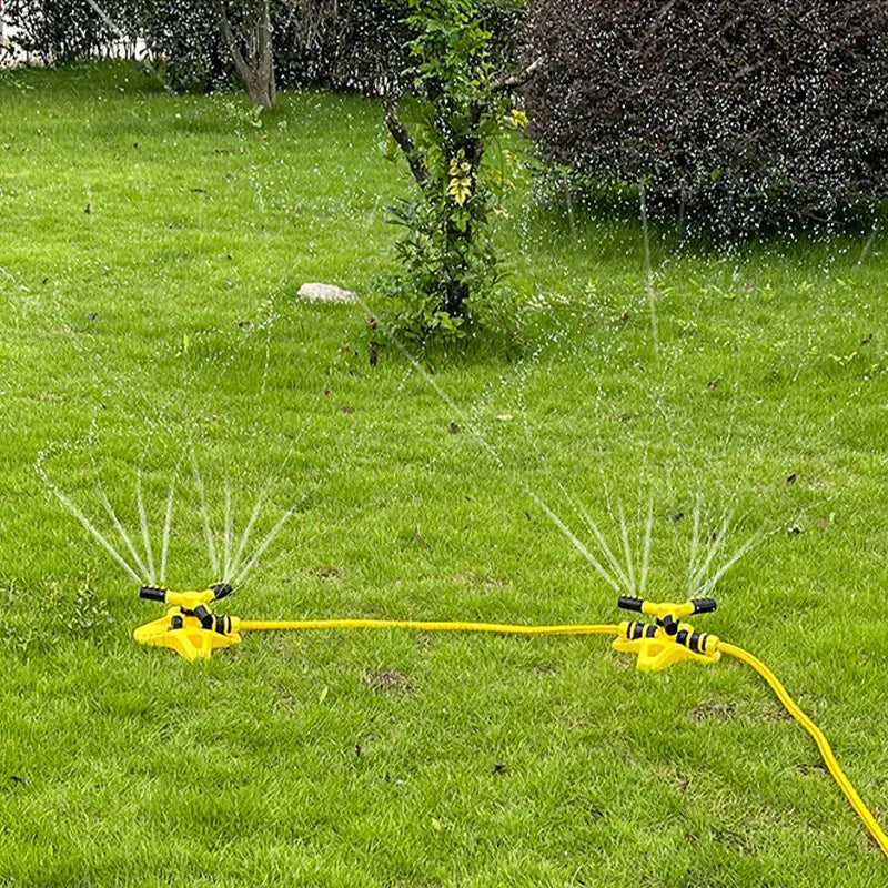 Yellow 360 rotary sprinkler spraying water across the lawn from rotating nozzle arms