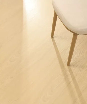 SPC click flooring plank close-up with pale cream wood grain under chair legs