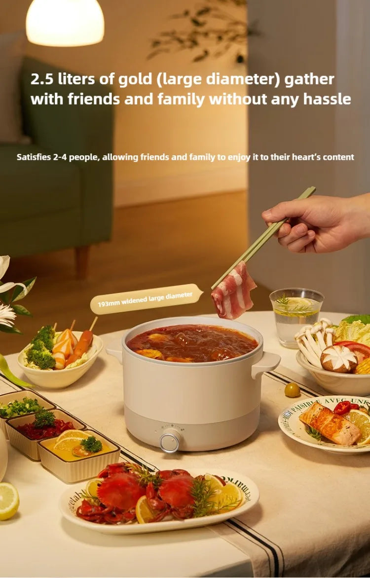 2.5L electric multi cooker with lid, warming soup on a table with serving bowls.