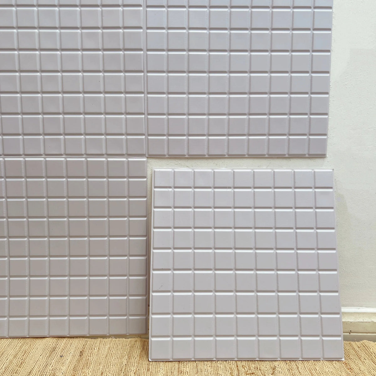 Square peel-and-stick backsplash tiles with glossy white finish and light gray grid lines (12 in x 12 in).