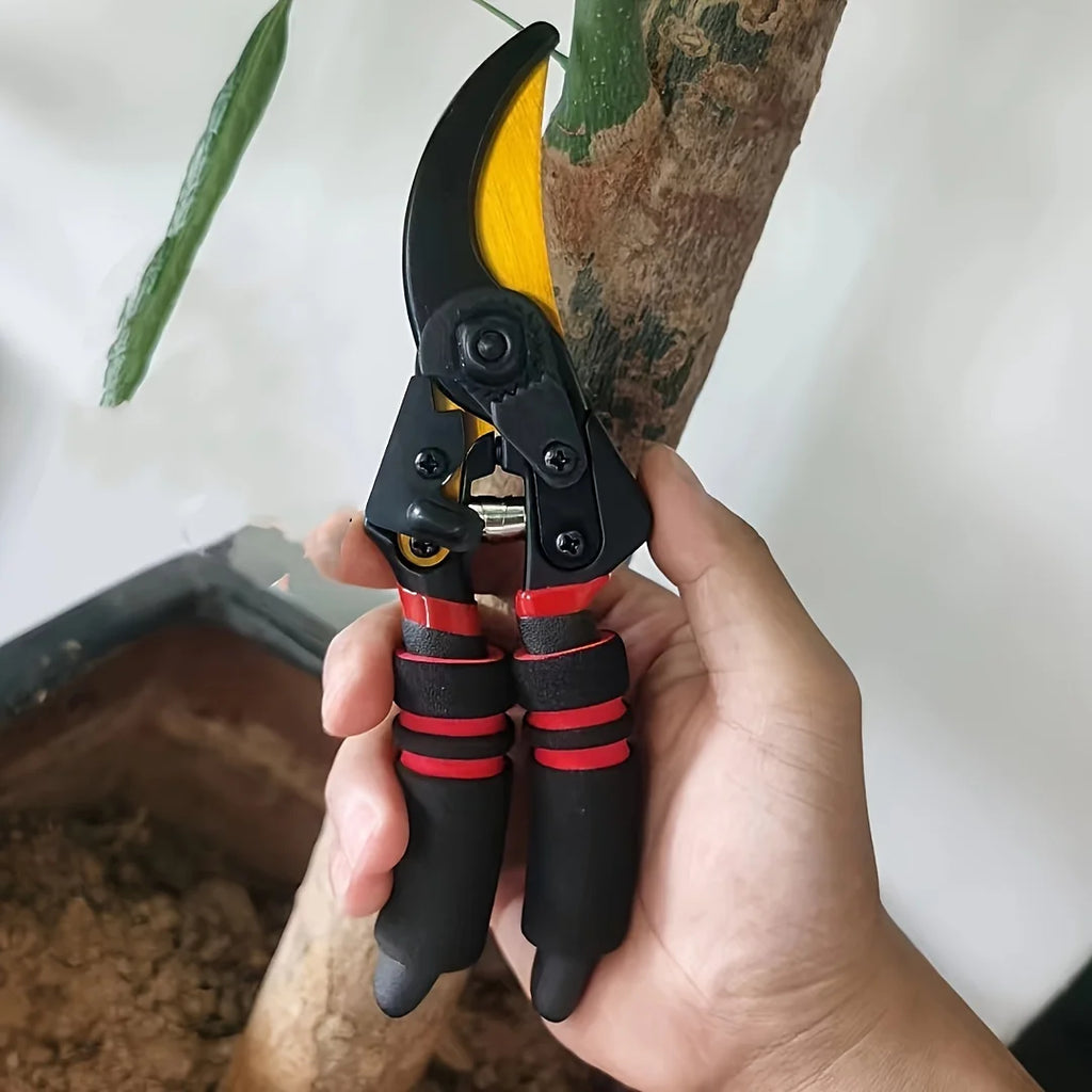 Pruning shears held in hand, yellow blade, black handles with red rubber bands