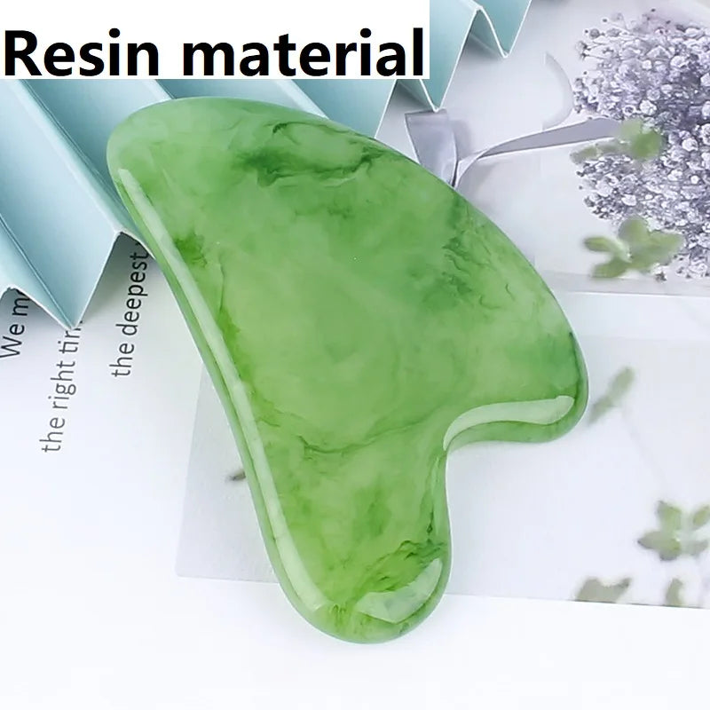 Heart-shaped, green marbled resin gua sha massage tool on a light surface.
