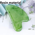 Heart-shaped, green marbled resin gua sha massage tool on a light surface.