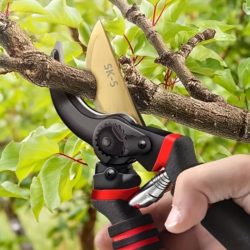 Garden pruning shears in hand, black handles with orange accents, curved yellow blade