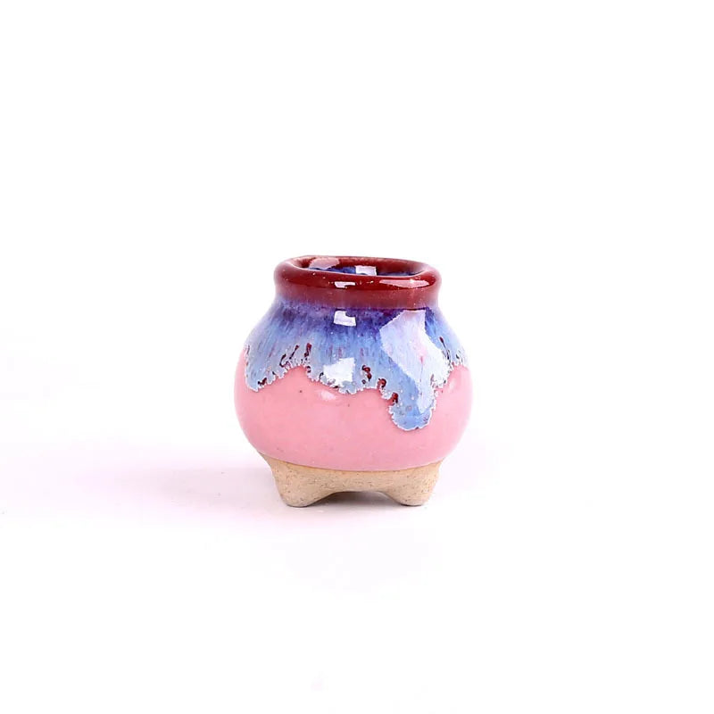 Mini ceramic flowerpot for succulent, pink body with blue drips and red rim, small tripod feet.