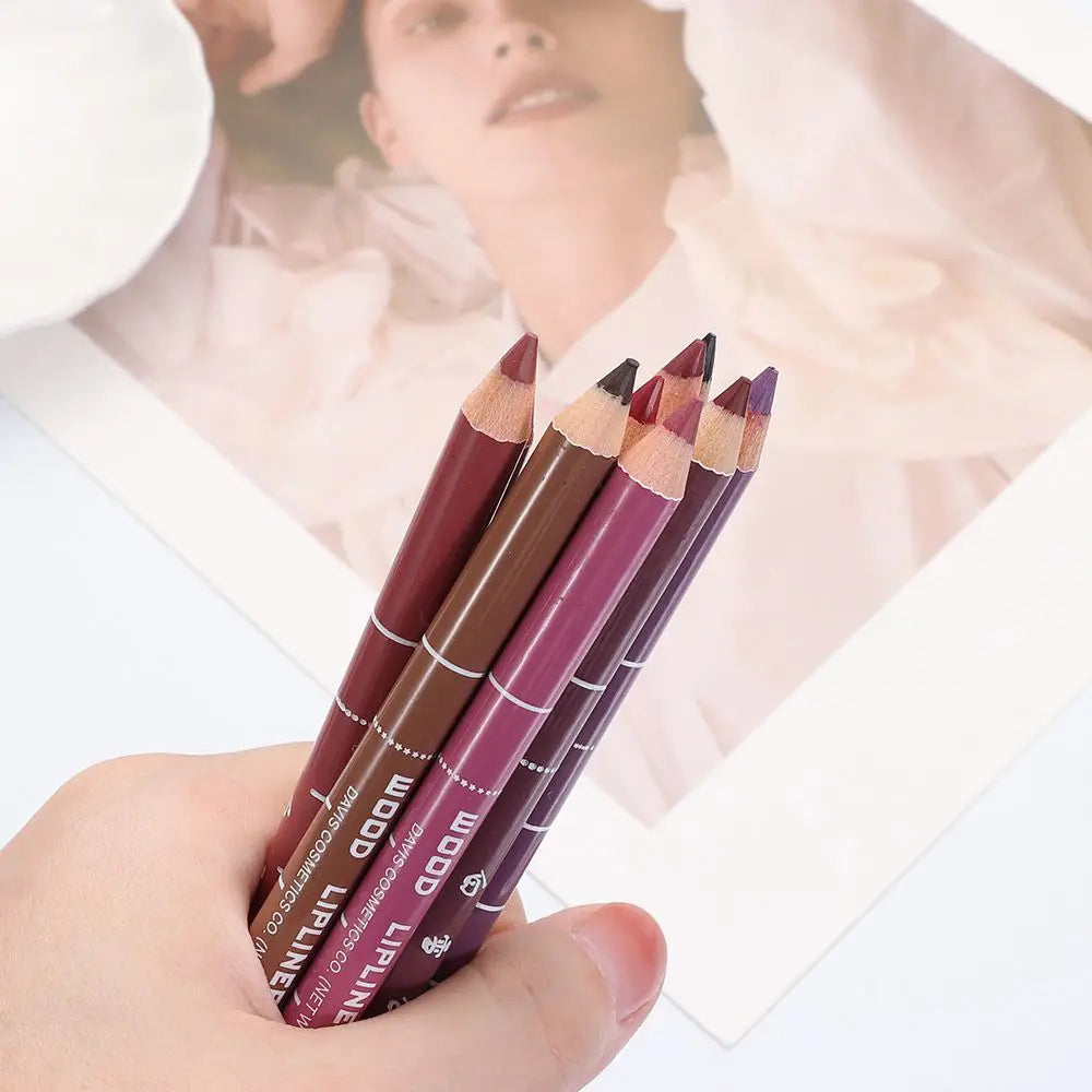 Hand holding multiple professional waterproof wood lip liner pencils in various matte shades of brown, plum, and red.