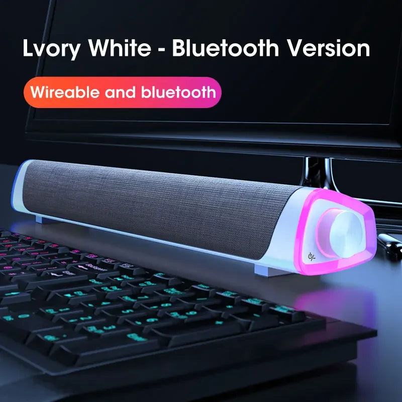 White Bluetooth speaker bar with gray fabric grille and pink LED glow by keyboard.