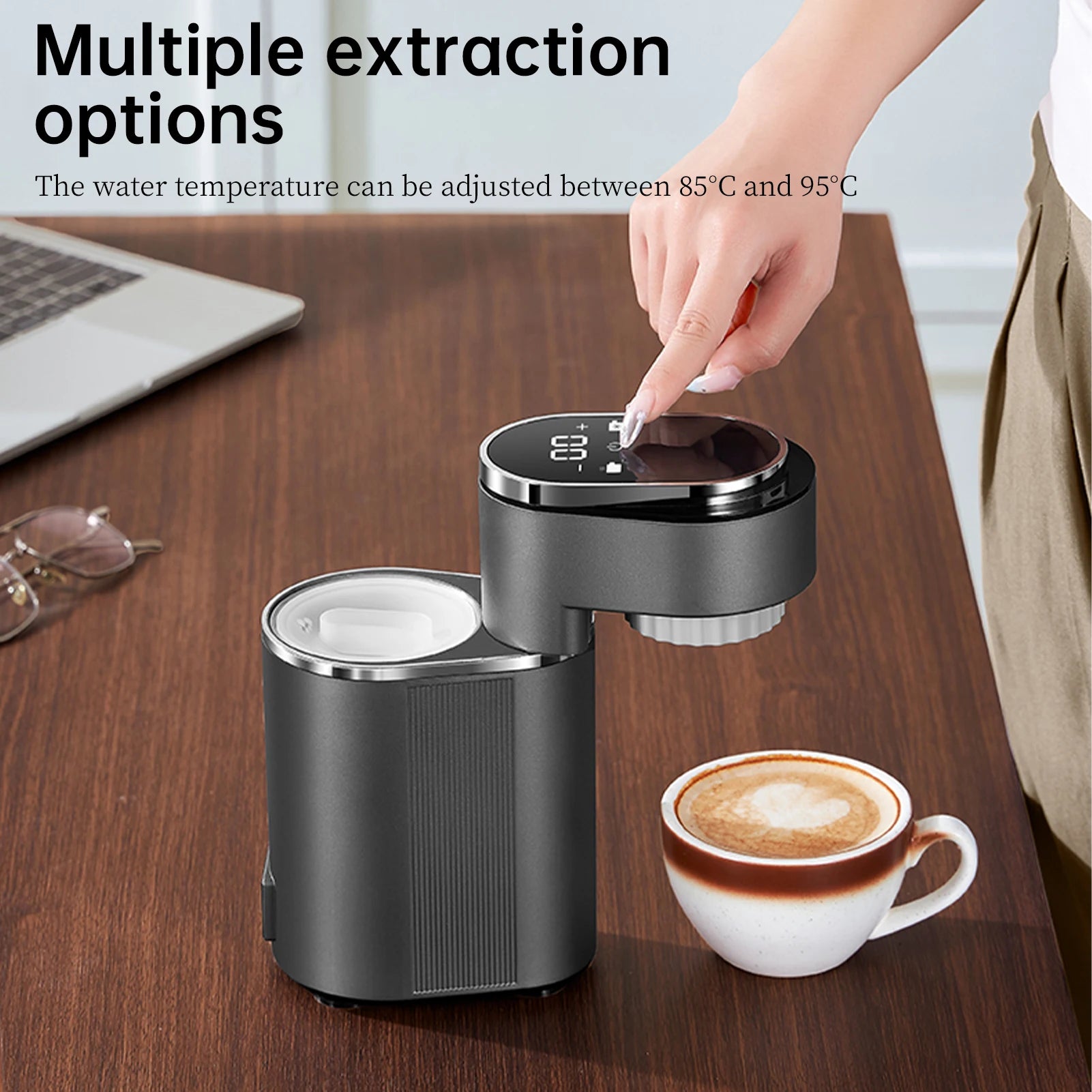 Compact dark gray portable coffee maker with digital touch temperature display on a desk next to a coffee cup.