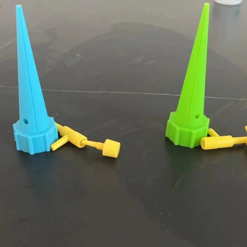 Pair of blue and green drip irrigation spikes with yellow connectors on surface.