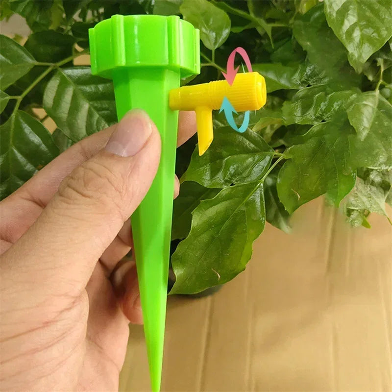 Green adjustable drip irrigation stake with yellow outlet, held near plant leaves