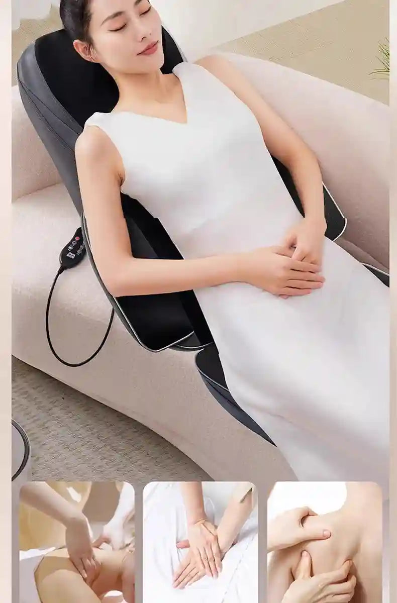 A woman in a white dress sits on a sofa using a sleek, black Shiatsu neck and back massager chair pad with a remote.
