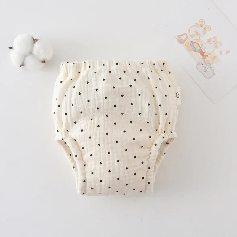 Cream baby cloth training diaper with black polka dot print, made of soft absorbent cotton fabric.