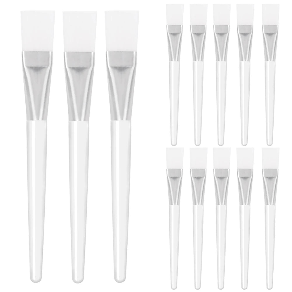 A set of face mask applicator brushes with white silicone heads, silver ferrules, and translucent white handles.