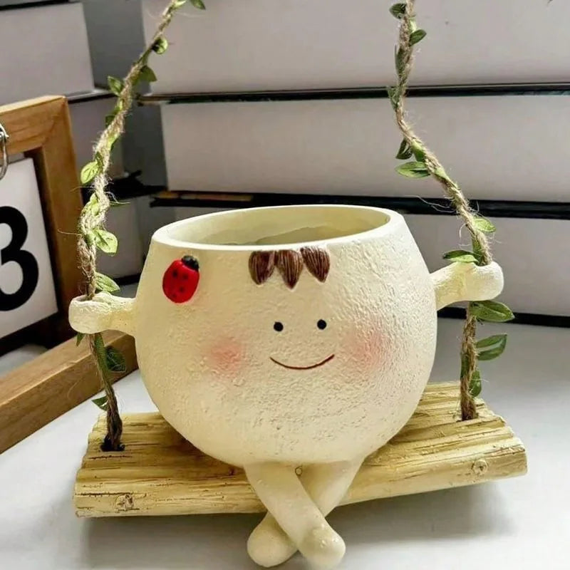 Cream hanging succulent planter with smiling face, ladybug detail and leafy plant inside