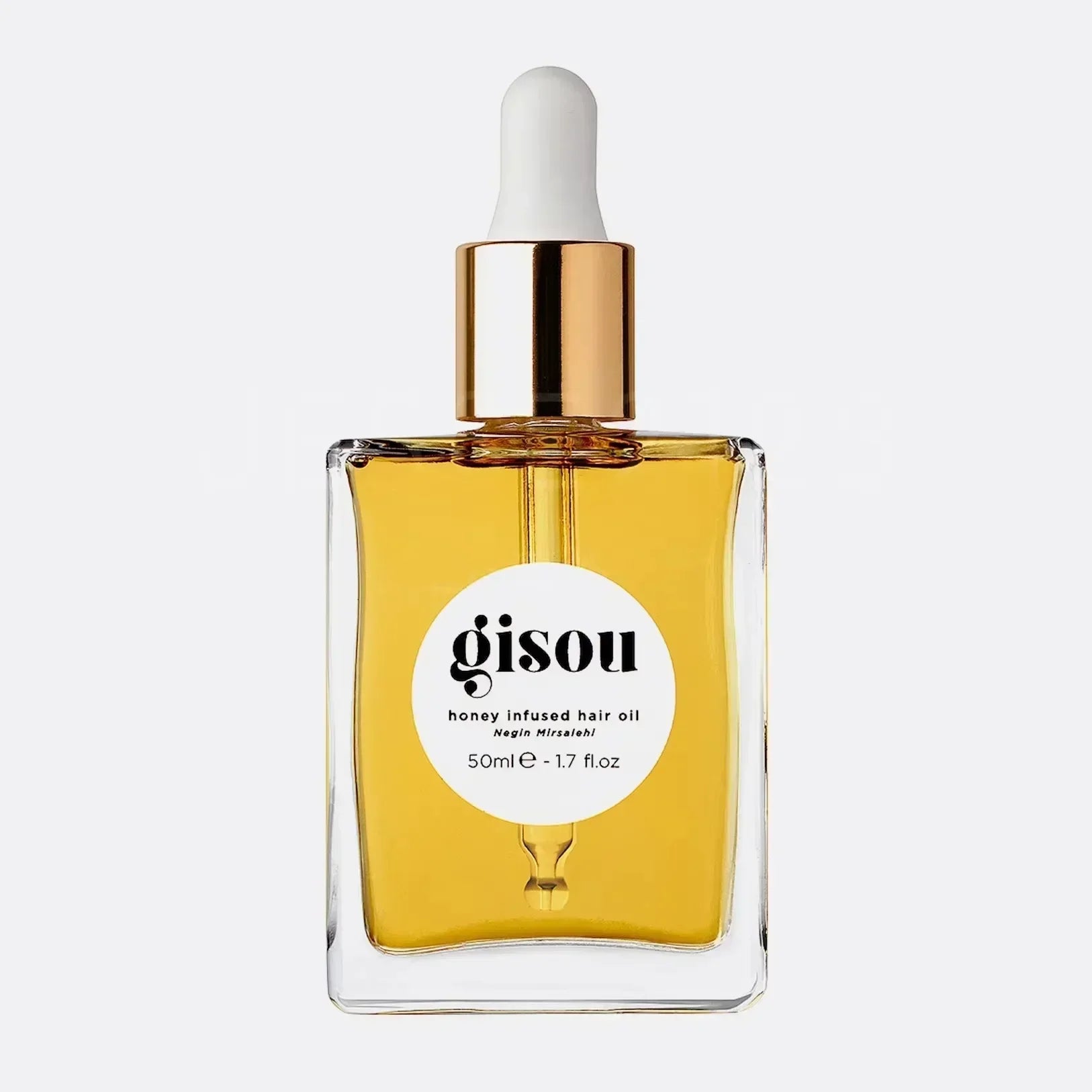 Gisou honey infused hair oil in a clear square glass bottle with gold dropper cap and white circular label.