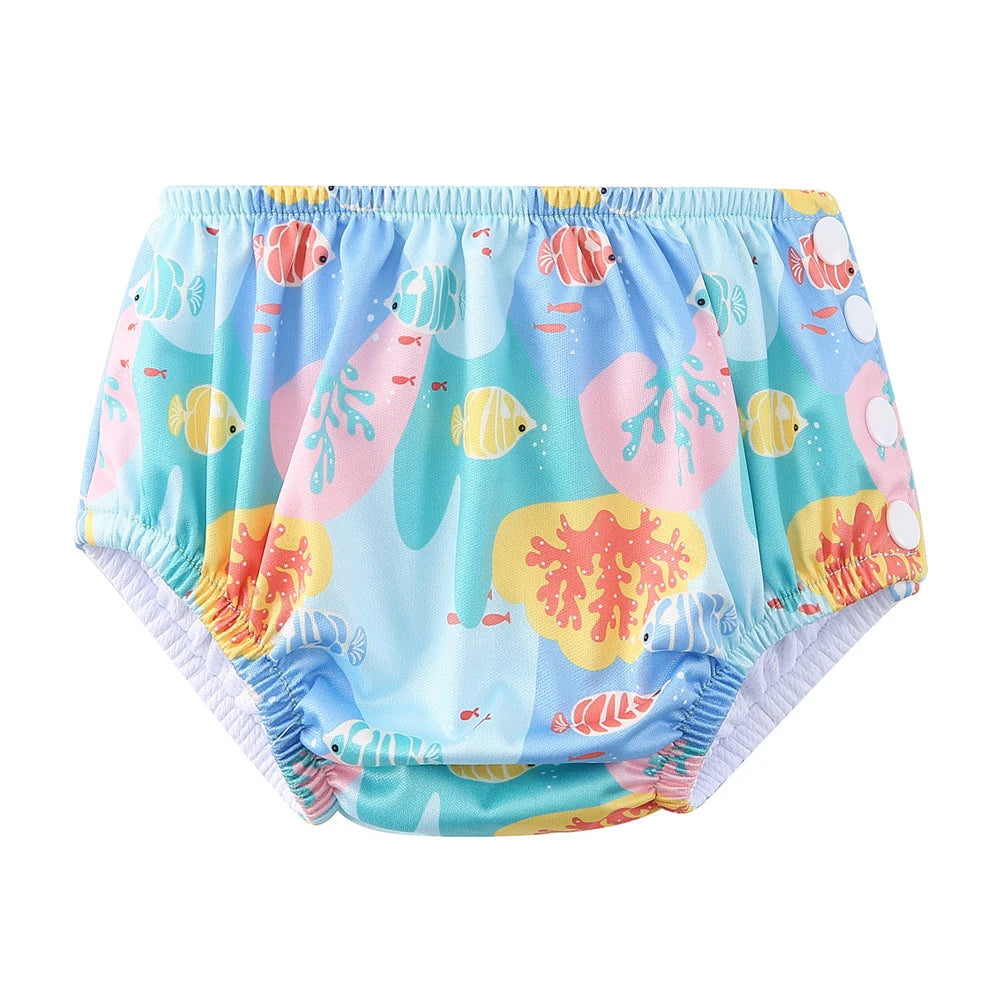 Reusable baby swim diaper in blue with colorful fish and coral reef print, featuring adjustable side snap closures.