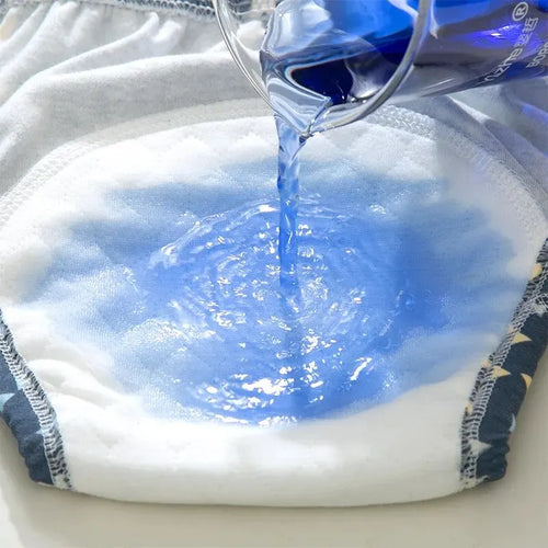 Absorbent baby training pants with star pattern being tested with blue liquid for leak-proof baby care performance.