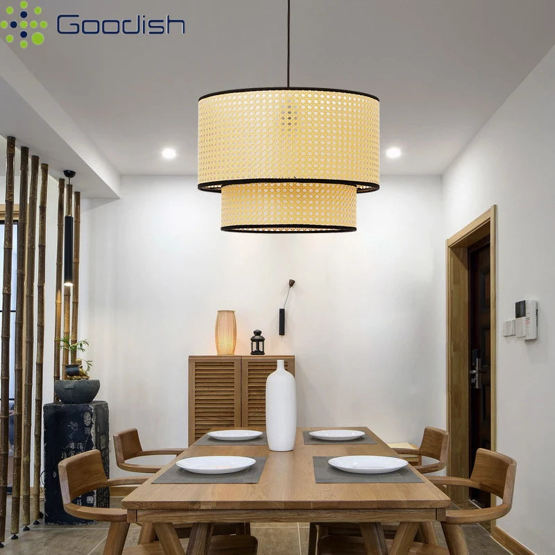 Two-tier drum pendant light with natural woven rattan shades and black trim, suspended over a dining room table.