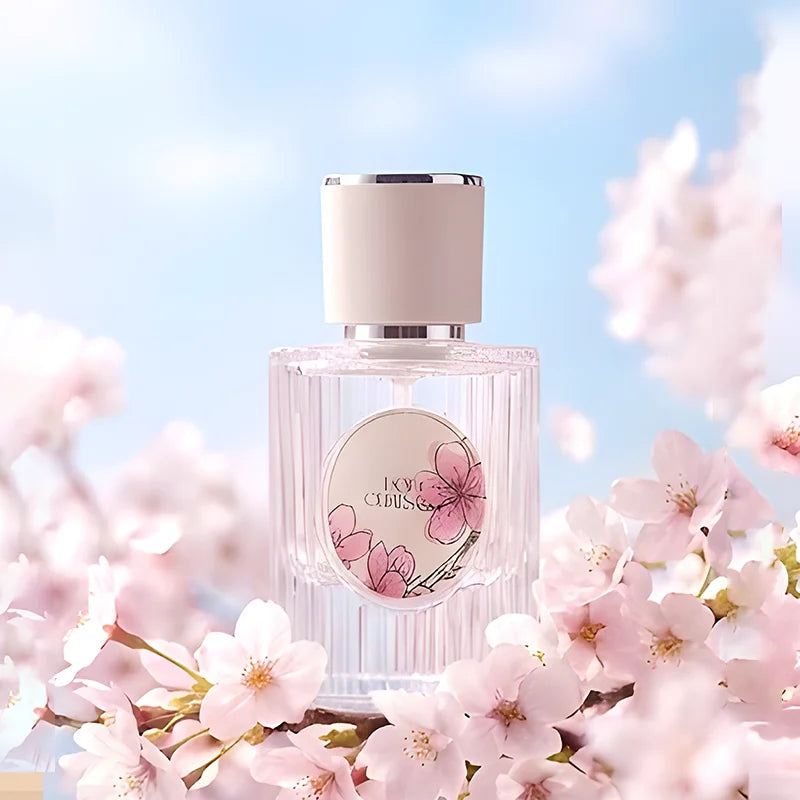 Elegant cherry blossom perfume bottle in glass with soft pink floral label surrounded by fresh sakura flowers.