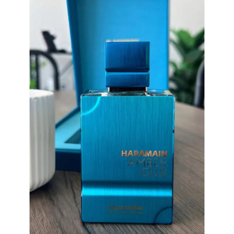 Al Haramain Amber Oud Aqua Dubai: Unisex 60ml oriental floral oud EDP in a sleek metallic blue rectangular glass bottle.