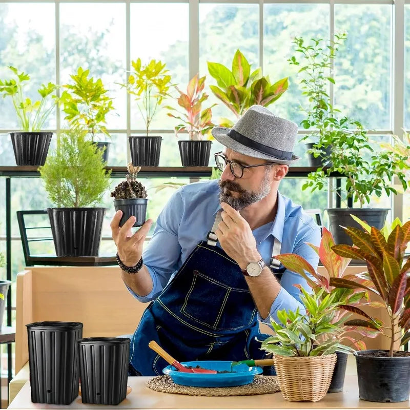 Black ribbed plastic plant pots with drainage holes, grouped on a table indoors