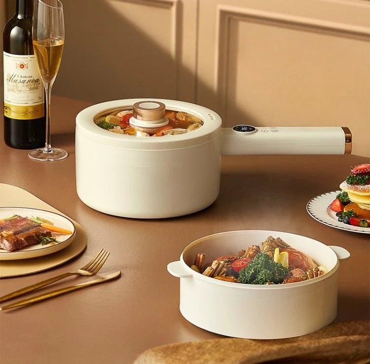 Electric hot pot on kitchen counter with lid and bowls of cooked food