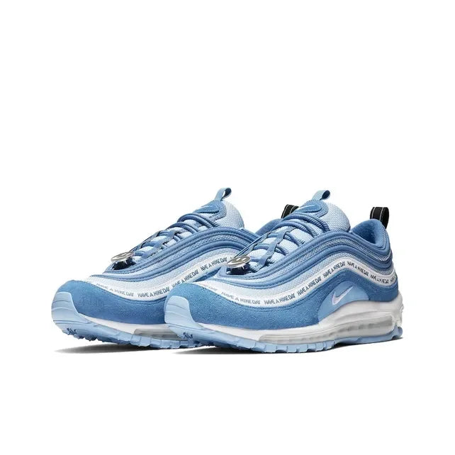 Light blue Nike Air Max 97 sneakers with suede overlays, "Have a Nike Day" text, and smiley face lace toggles.