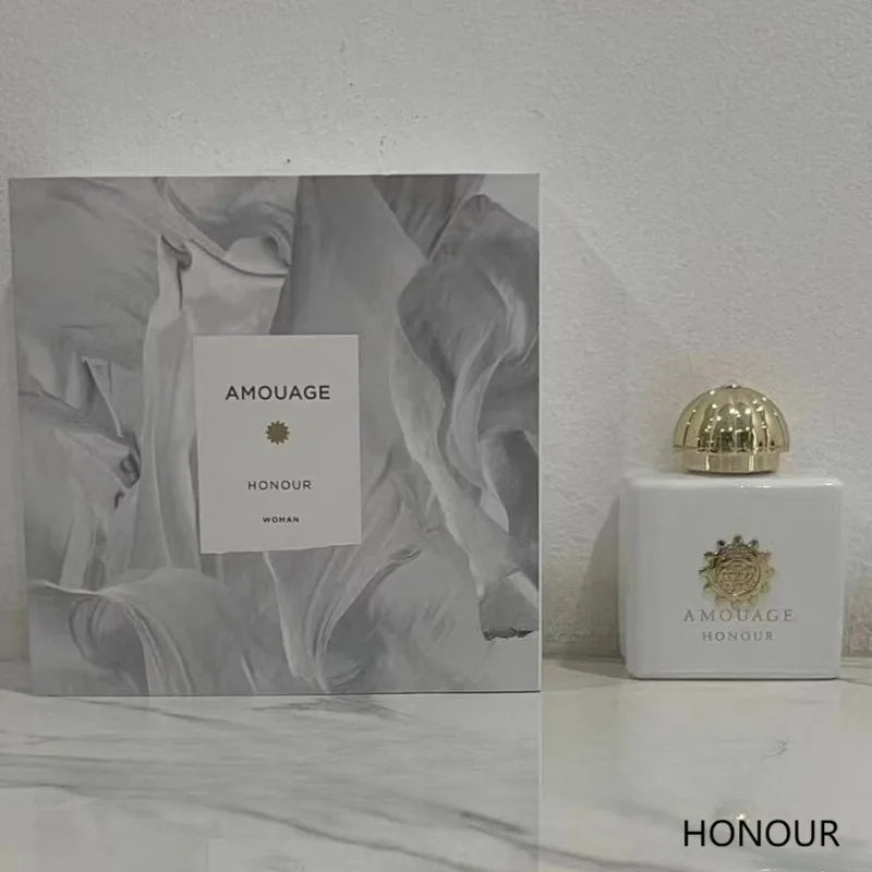 Amouage Honour Woman 100ml perfume, white glass bottle with gold cap and emblem, next to artistic floral gift box.
