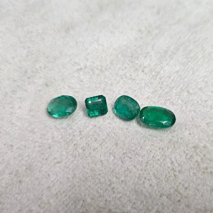 Loose green emerald-cut gemstone mix, including round and rectangular stones on felt