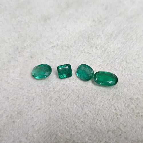 Loose green emerald-cut gemstone mix, including round and rectangular stones on felt