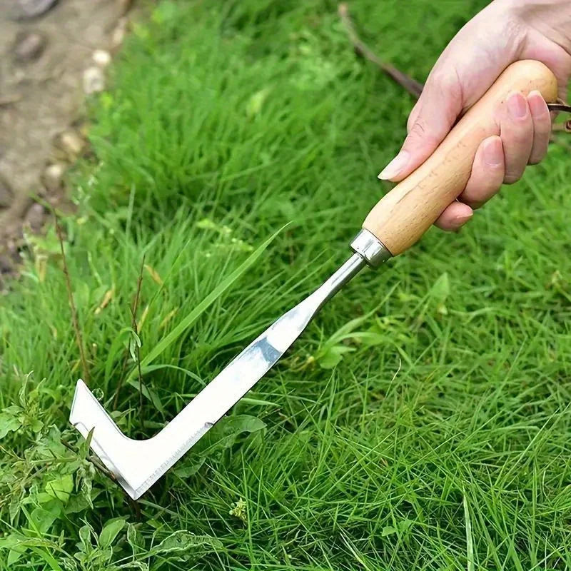 Hand holding L-shaped stainless steel gap weeding tool with wooden handle on green grass.