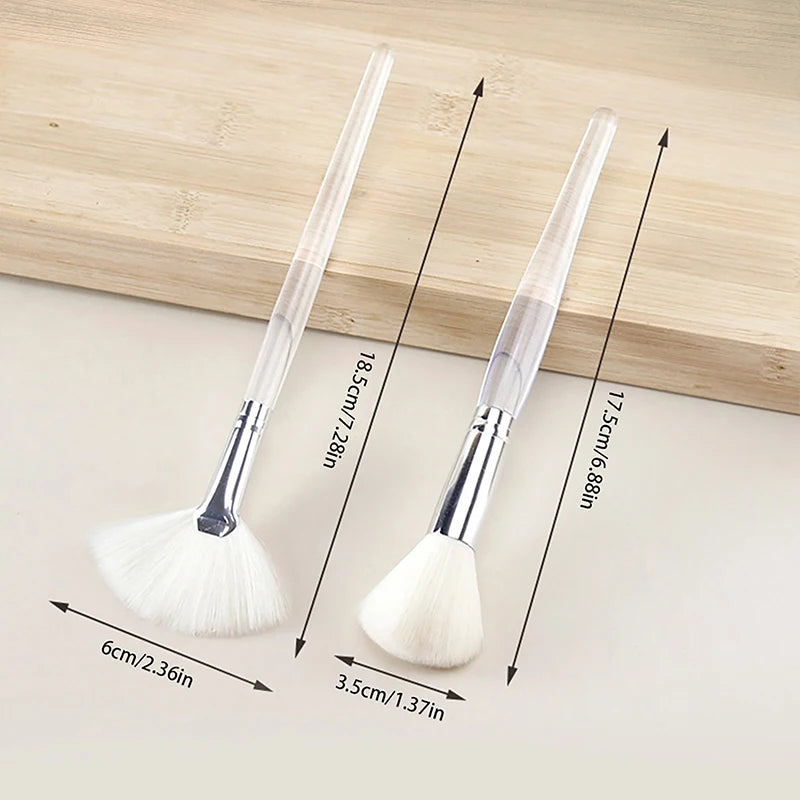 Two portable facial skincare brushes with soft white bristles and clear acrylic handles for mask and cleansing use.
