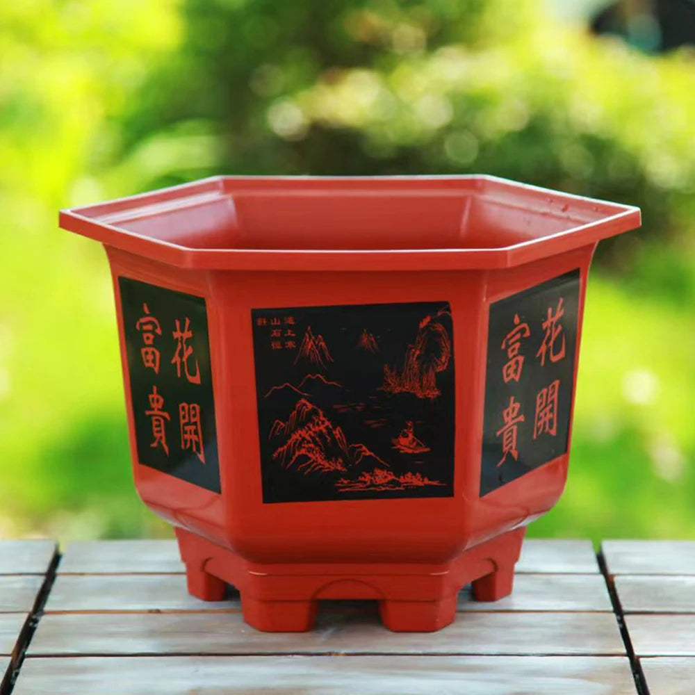 Red plastic planter pot with decorative side panels and four stub feet