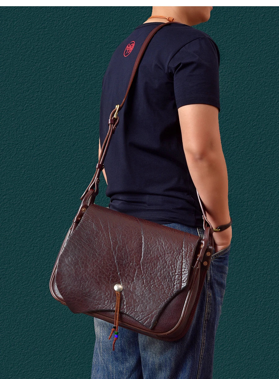 Vintage handmade dark brown cowhide leather messenger bag with flap, brass button, and adjustable shoulder strap.