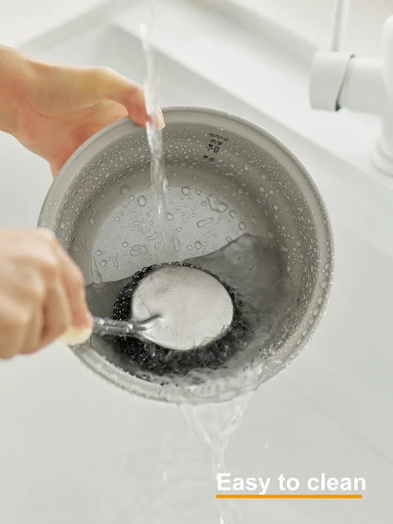 Smart white electric rice cooker pot being filled with water for easy cleaning